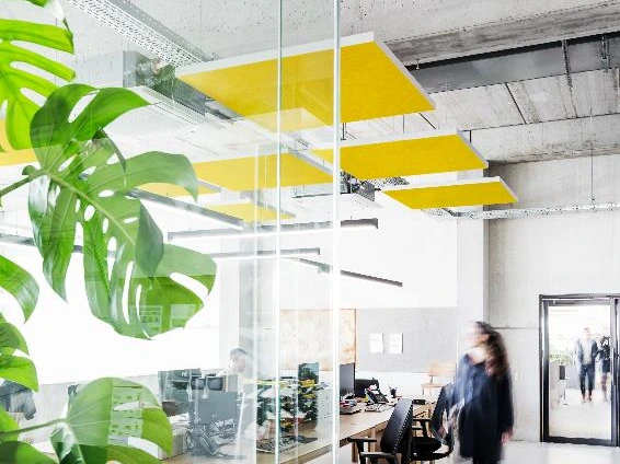 open space moderne vitré avec des panneaux en feutre jaune qui pendent du plafond