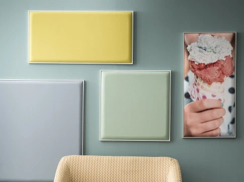Cadres acoustiques colorés accrochés sur un mur derrière un fauteuil