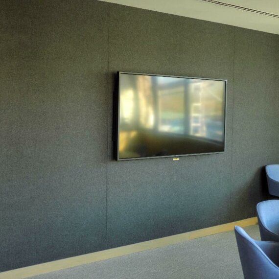 Salle de réunion équipée d'une télévision installée au mur sur des panneaux en feutre noir